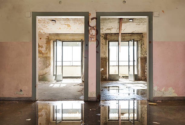 Water reflects two doorways in abandoned building
